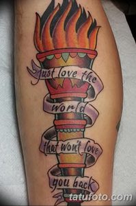 Фото татуировки на ноге: тату факела с надписью 'Just love the world that won't love you back'. Стиль олд скул.