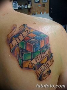 Фото тату кубика Рубика на плече. Яркий рисунок с надписями 'Life's a Puzzle, Grab It'. Идеальный эскиз для любителей головоломок.