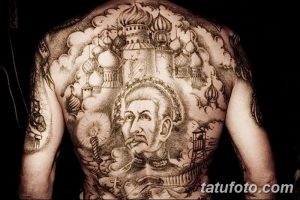Фото татуировки на спине мужчины: изображение собора, портрет мужчины, облака и другие религиозные символы. Черно-белая татуировка, покрывающая всю спину.