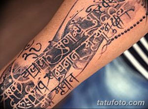 Фото тату на руке: длинная полоса санскритского текста, выполненная в технике blackwork. Детализированный рисунок татуировки, покрывающий большую часть предплечья.