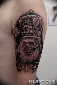 Фото тату черепа в царской короне на плече. Детализированный черно-серый рисунок с реалистичными тенями и проработкой деталей.