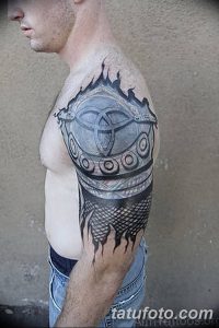 Фото тату на плече с изображением викингского шлема в стиле Blackwork. Геометрические узоры и плотная штриховка.