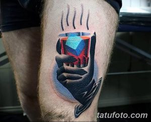 Фото тату на ноге, изображающее руку, держащую светящийся куб. Яркие цвета и реалистичная проработка деталей.