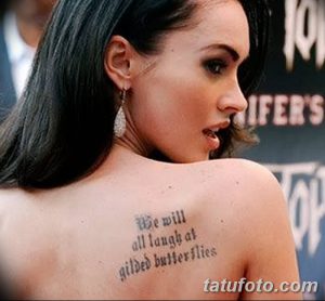 Фото тату: цитата 'We will all laugh at gilded butterflies' на лопатке Меган Фокс, выполненная черными чернилами, изящный шрифт.