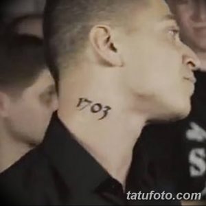 Черно-белое фото татуировки с цифрами '1703' на шее мужчины. Простой дизайн, четкие линии, небольшая татуировка, расположенная сбоку шеи.