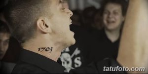 Фото татуировки с цифрами '1703' на шее Эминема во время выступления, демонстрирующее ее расположение и размер.