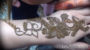 Фото тату хной на руке, сложный восточный орнамент, коричневые тона, процесс нанесения, женская рука, детальная проработка.