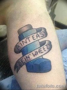 Фото тату на руке с изображением ингалятора и надписью "Ain't Easy Bein' Wheezy". Рисунок татуировки выполнен в простом, мультяшном стиле.