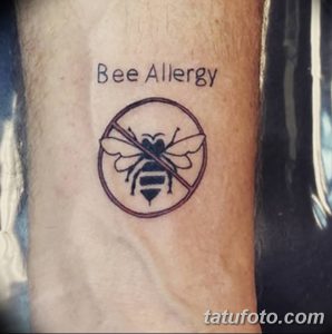 Фото тату на предплечье: перечеркнутая пчела в круге, надпись 'Bee Allergy'. Простая и понятная татуировка для аллергиков.
