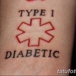 Фото тату: Простая татуировка с надписью "TYPE 1 DIABETIC" и красным символом медицинского креста, расположенная на запястье.