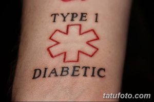 Фото тату: Простая татуировка с надписью "TYPE 1 DIABETIC" и красным символом медицинского креста, расположенная на запястье.