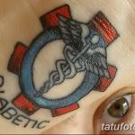 Фото тату на руке с изображением символа диабета – синего круга с белым крестом и надписью 'Diabetic'. Предупреждение об опасности.