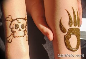 Фото тату хной на предплечьях: череп с костями и отпечаток лапы медведя, выполненные коричневой хной.