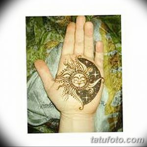 Фото тату Mehndi: детализированный рисунок солнца и луны с растительными элементами, нанесенный на ладонь.
