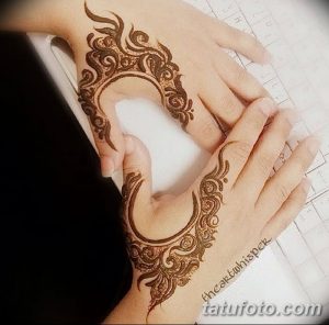 Фото тату Mehndi: изящный рисунок полумесяца, украшенный сложным орнаментом, нанесенный на руку.