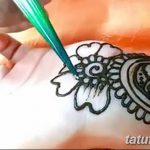 Фото процесса нанесения тату мехенди на руку. Мастер аккуратно наносит узор хной, используя специальный инструмент.