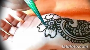Фото процесса нанесения тату мехенди на руку. Мастер аккуратно наносит узор хной, используя специальный инструмент.