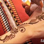 Фото процесса нанесения тату мехенди на руку. Мастер аккуратно наносит узор хной, создавая красивый и сложный рисунок.