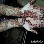 Фото тату хной на руках: изящные восточные узоры, украшающие ладони и запястья, выполненные в коричневых тонах, на темном фоне.