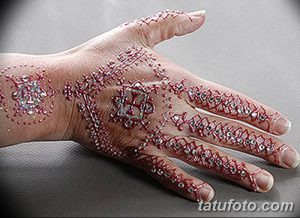 Фото тату хной на руке, демонстрирующее сложный узор с использованием серебристых блесток и ярких цветов. Идеально для особых случаев.