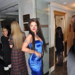 Фотография женщины в синем платье с татуировкой на руке. Видна татуировка, платье и аксессуары.