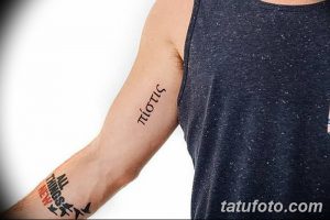 Фото тату с греческим словом на предплечье. Черный цвет, тонкие линии, минималистичный дизайн. Идеи для тату на память.