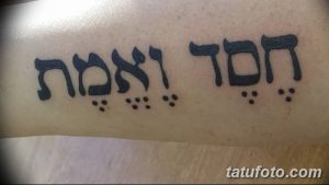 Фото тату: татуировка с надписью на иврите, выполненная черными чернилами, расположена на руке. Простой и выразительный дизайн.