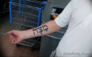 Фото тату: небольшая надпись на иврите на запястье. Черные чернила, простой шрифт. Минималистичный дизайн.