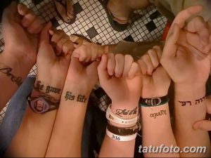 Фото тату: четыре руки с татуировками надписей на запястьях, символизирующих семейные ценности и веру. Черные чернила, четкий шрифт.