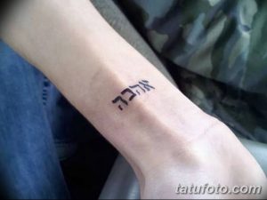 Фото тату на запястье: маленькая черная ивритская надпись, выполненная простым шрифтом. Небольшая и аккуратная татуировка.