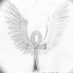 Черно-серый эскиз татуировки Анх с расправленными крыльями по бокам. Рисунок выполнен в графическом стиле.