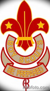 Фото тату с изображением лилии, окруженной надписью "Boy Scouts" и девизом "Be Prepared". Рисунок выполнен в ярких красных и золотых тонах.