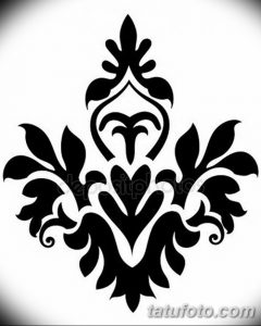 Черно-белое фото татуировки с изображением стилизованного орнамента, напоминающего лилию. Изящные линии и плавные переходы.