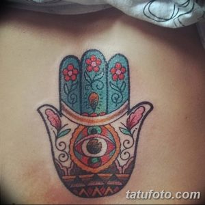 Фото цветной татуировки Хамсы на спине. Рисунок выполнен в ярких, насыщенных цветах с использованием цветочных мотивов и геометрических узоров.