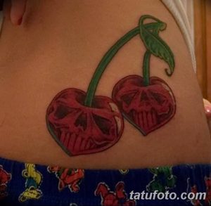 Фото тату вишни с изображением черепа внутри. Красные вишни с зелеными листьями и мрачным черепом. Оригинальный и жуткий рисунок для любителей готики.