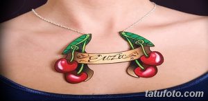 Фото татуировки с вишней и лентой, на которой написано имя. Красный, зеленый и золотой цвета.