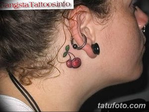 Фото тату двух вишен на шее, рядом с ухом. Небольшой и изящный рисунок, подчеркивающий индивидуальность.
