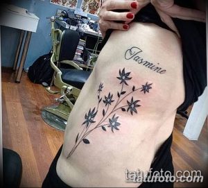 Фото татуировки с изображением ветки жасмина и надписи "Jasmine" на женском боку. Элегантный и персонализированный дизайн.
