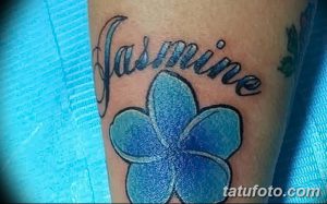 Фото тату на руке: Голубой цветок жасмина с надписью "Jasmine". Нежный и женственный рисунок татуировки.