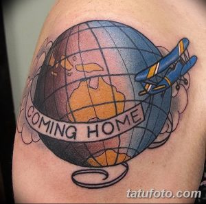 Фото тату: красочный рисунок глобуса с летящим самолетом и надписью 'Coming Home' в стиле олдскул на плече. Отличный эскиз тату для любителей путешествий.