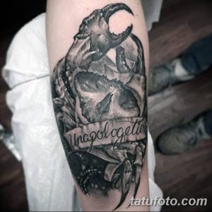 Фото тату: черно-белая татуировка краба, обвивающего череп, стиль blackwork, темные тона, готический стиль, надпись 'Unapologetic'.