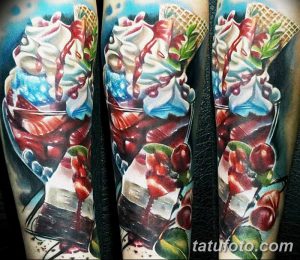 Фото тату на руке с изображением многослойного десерта в высоком бокале. Реалистичный стиль, яркие цвета и детализированная проработка.
