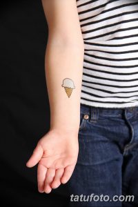 Фото тату: маленькое мороженое в вафельном рожке, простой рисунок на руке ребенка, минималистичный стиль.