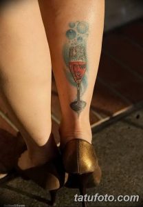 Фото татуировки на лодыжке с изображением бокала красного вина и пузырьков. Тату выполнено в реалистичном стиле.