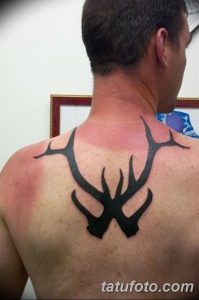 Фото стильной татуировки оленьих рогов на спине. Изображение выполнено в черном цвете с использованием геометрических элементов.
