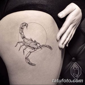 Фото тату геометрического скорпиона на женском бедре. Черно-белый рисунок татуировки с использованием острых углов и линий.