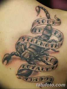 Фото тату скорпиона на груди с лентами, содержащими слова 'Soul', 'Strength', 'Loyalty'. Реалистичный черно-серый рисунок татуировки.