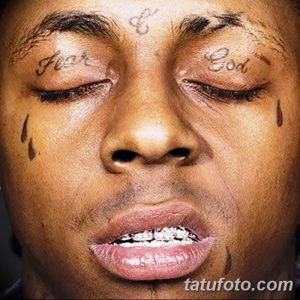 Фото тату на лице рэпера Lil Wayne. Черные татуировки в виде надписи 'For God' на лбу и капель слез под глазами.