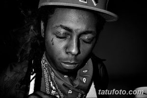 Фото тату на лице рэпера Lil Wayne. Черные татуировки в виде капель слез под глазами и надпись 'Fear God' на лбу.