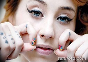 Фото тату на пальцах женщины. На пальцах изображены небольшие цифры, точки и миниатюрные рисунки.